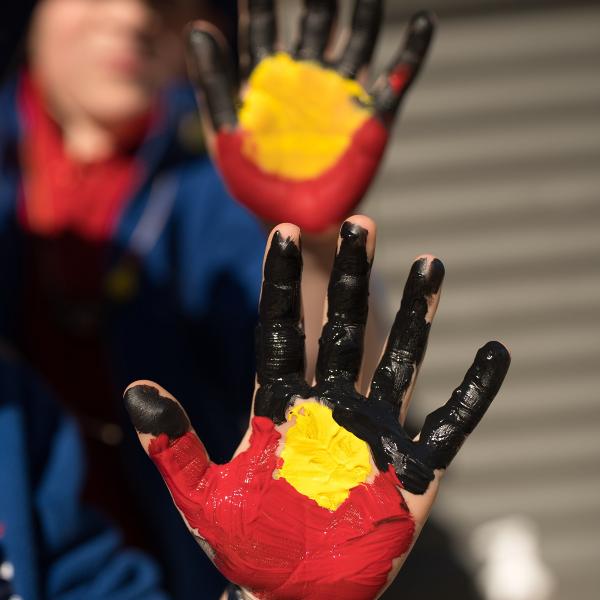 Kids hands painted to represent the Aboriginal flag